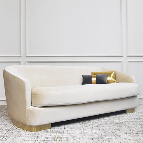 Angled view of the Rever Curved sofa, 3 seater, modern mid-century design. Style this deep sofa with the Mesh gold boudoir cushion, matching the brushed gold steel legs. 