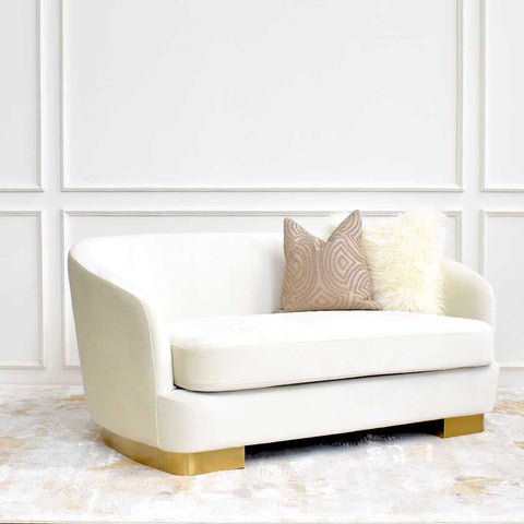 Side angle of the Rever Curved Sofa showcasing its asymmetrical silhouette, recessed gold pedestal base, and sleek profile.