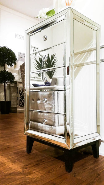 Etienne 5-Drawer Tall Boy Dresser in all-hand-cut mirrors and reflects light beautifully in a modern luxury living room.