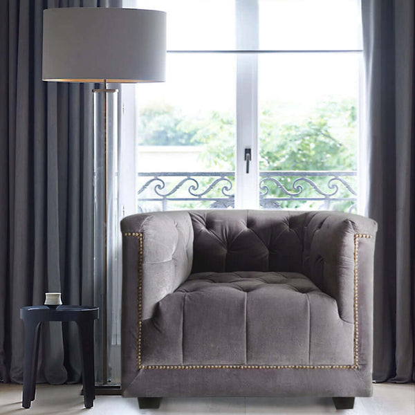 Earl Chesterfield Armchair next to a acrylic lamp and window, showcasing its velvet upholstery and tufted back in a cozy living room setting.