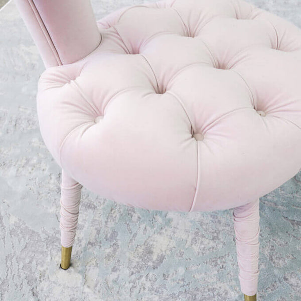 Zoomed in pink chair with tufted fabric details on cushion seat.