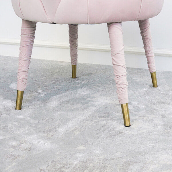 Zoomed in blush pink chair leg with gold tips on feet.