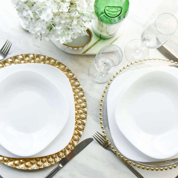Top view of table set up with white plates and gold Barbican glass charger collection.