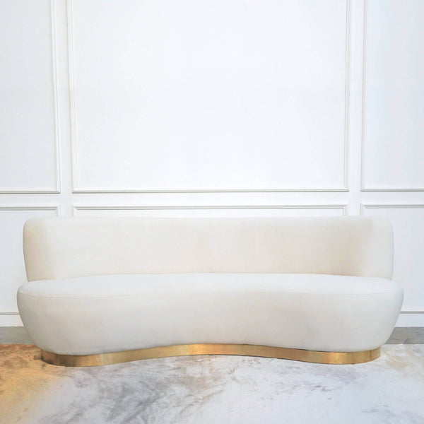 Full view of the Eclipse curved sofa, easy clean ivory velvet upholstery perched on a brushed matte gold steel base.