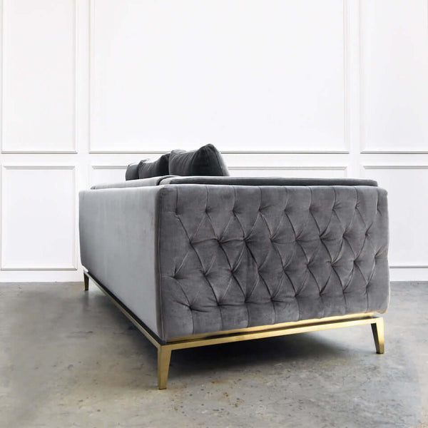 Angled view of grey velvet Fitzgerald sofa showing modern silhouette and cushion details.