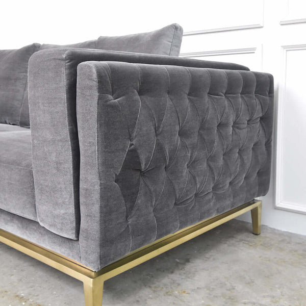 Arm-side detail of grey velvet Fitzgerald sofa featuring clean tufted lines and metal trim.