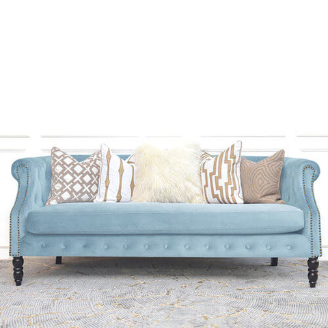 Fayette pastel blue sofa, a petite and slim sofa designed in a modern lux Chesterfield style. Prop with ivory cushions for a brighter look. 