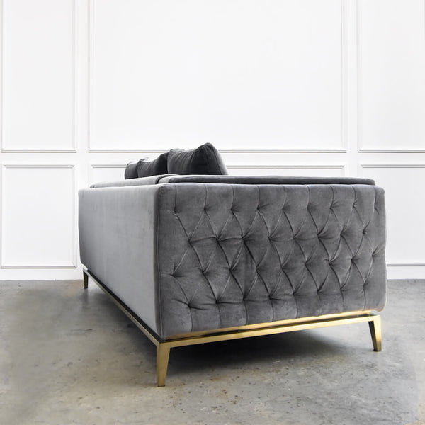 Side view of hand tufted details on Fitzgerald sofa featuring the brushed gold stainless steel leg frames.