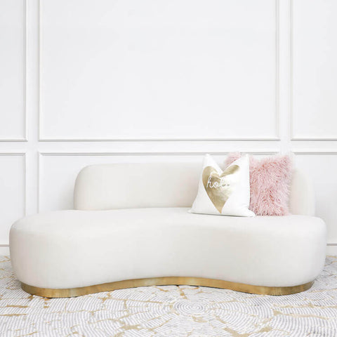 Infiniti Curved sofa, a Vladimir Kagan inspired curved sofa style, plush ivory cream velvet. Pink furfural cushion and White gold Square cushion perched on a curved gold plinth base.