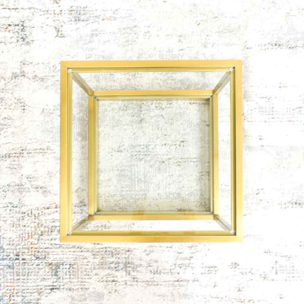 Top view of a gold side table with a minimalist design. It is designed with a square frame and a glass tabletop.