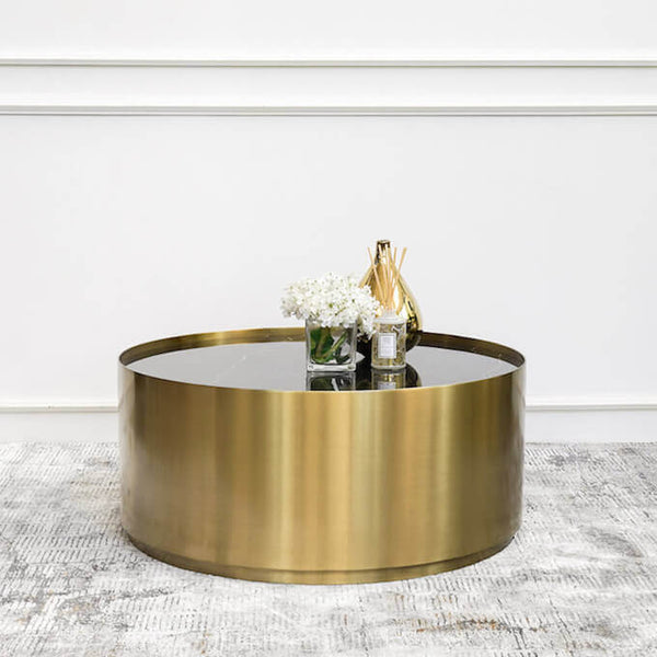 Side view of the brushed stainless steel gold drum base of the Marc Round Marble Coffee Table. 