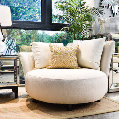 Paramour Round Sofa upholstered in lush beige velvet, styled in a cozy corner with a brass table lamp, neutral area rug, and art deco side table.