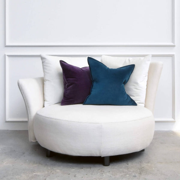 Custom Paramour Round Sofa placed near a window with sheer curtains, layered with indigo and teal throw pillows.