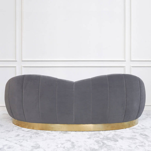 Heart shape backrest on the Primrose curved sofa, with brushed stainless steel gold base plinth.