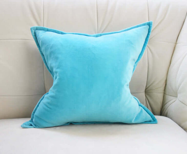Fluffed up blue velvet cushion on ivory velvet sofa.