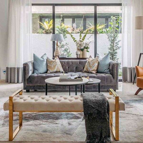 Our button-tufted Earl Chesterfield Sofa in light grey velvet, and Lisse Bench featured in a modern luxury landed home interior by Arete Culture. The perfect affordable luxury sofa to elevate your home.