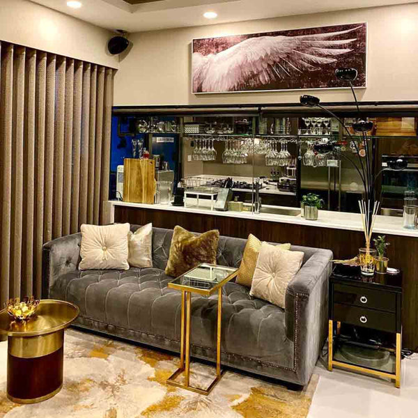 A customer's Singapore condo featuring the grey Esquire Chesterfield sofa. This luxurious button-tufted velvet couch is the perfect centerpiece for a modern living room, shown here with gold accent tables and stylish home decor.