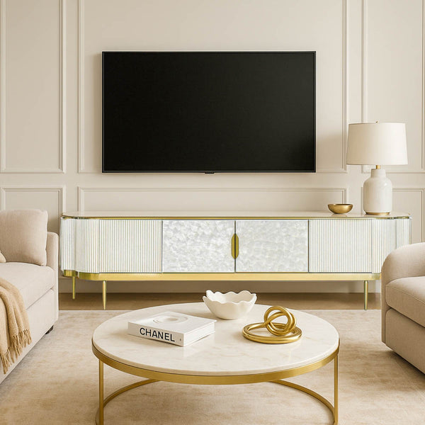 Elegant Perla white wood TV console with shimmering mother-of-pearl doors and brushed gold accents, creating an airy, timeless feel in a modern white and gold living room.