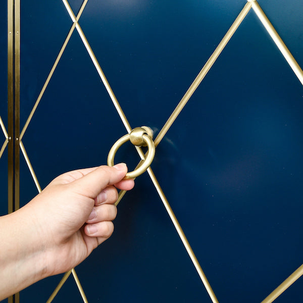 Hand holding the Valentino Cabinet Gold Ring Handle.