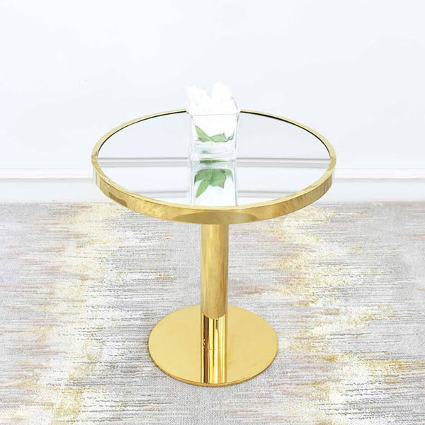Vis-a-vis Round Coffee Table (grande) with mirrored table top inset stainless steel polished gold rim that joins a pedestal polished gold round base. In glossy polished gold, the round table is decorated with white peony flower in a square vase, and sits on a luxury gold grey rug in a modern living room.
