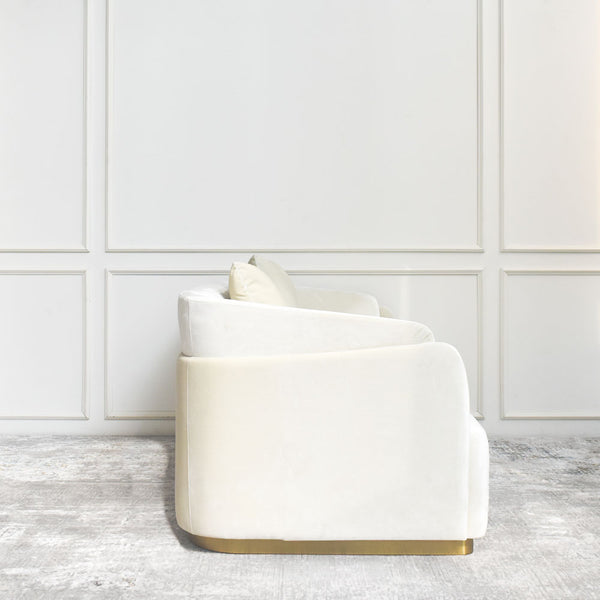 Elegant double-curved sofa in plush cream velvet with metallic gold base accents.