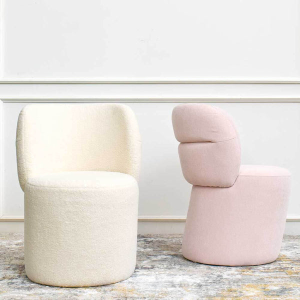Side view of pink bonbon vanity chair, front view of ivory boucle accent chair.