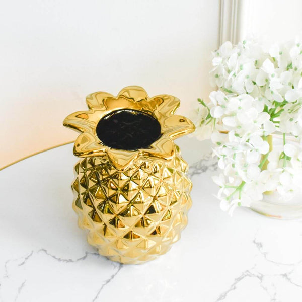 Ceramic pineapple gold jar, versatile decor piece.