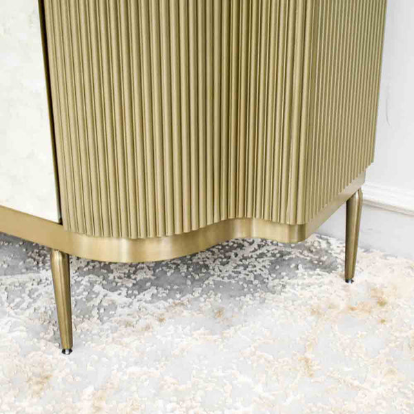 Close up look of the slim brushed gold legs on Perla cabinet.