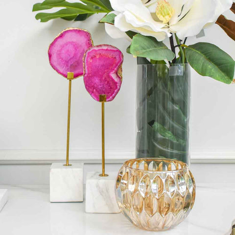 Natural pink agate stones, with gold edges on white marble block stand.