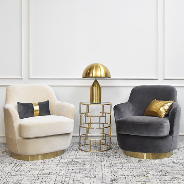 Rever Armchairs in grey and cream velvet displayed side by side with a sleek side table, styled in a bright, modern interior.