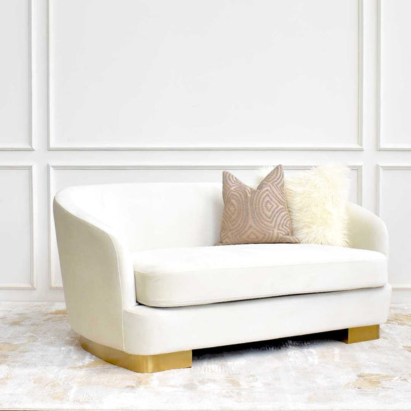 Side angle of the Rever Curved Sofa showcasing its asymmetrical silhouette, recessed gold pedestal base, and sleek profile.